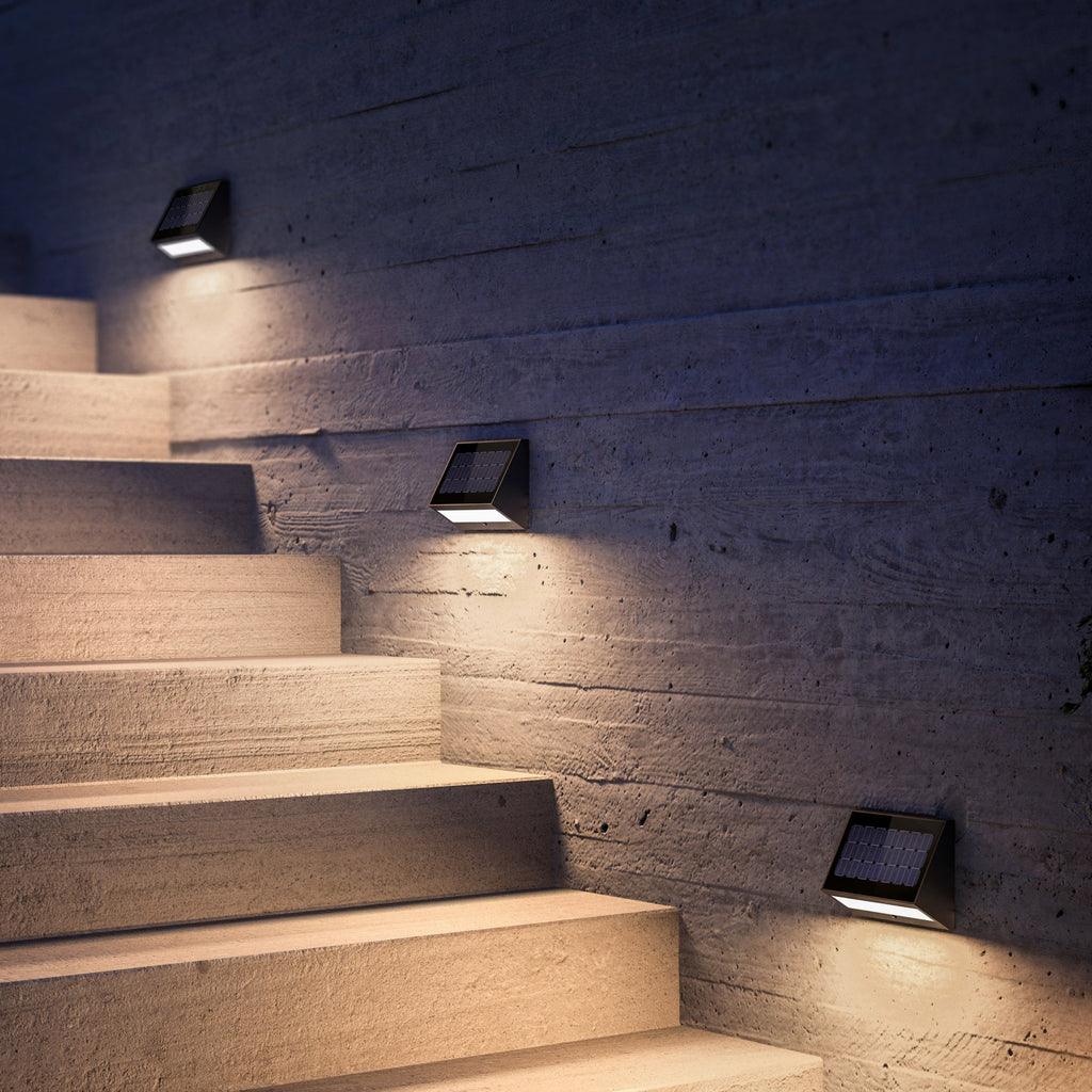 Stairway with wall-mounted lights on a textured wall at night.