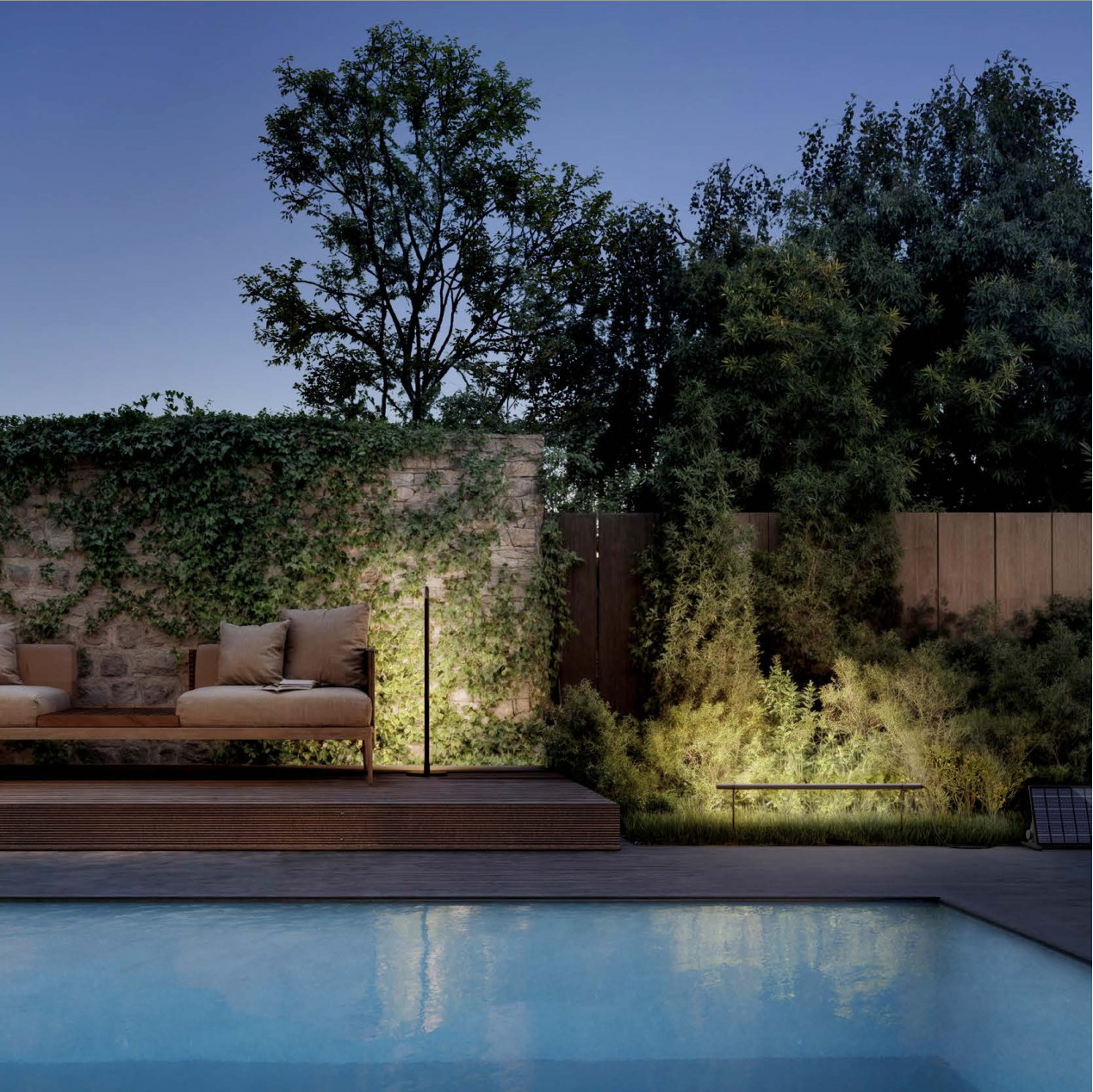 Outdoor seating area by a pool with a stone wall and greenery